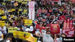 Demonstrators holding placards sit during a protest against the military coup outside the US Embassy in Yangon, Myanmar, Feb. 16, 2021.