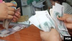 រូបឯកសារ៖ ប្រជាពលរដ្ឋខ្មែរ​រាប់​លុយ​រៀល​ ដែល​ជា​រូបិយប័ណ្ណ​​ជាតិ ​នៅតូប​ដូរ​លុយ​ក្នុង​ស្រុក​មួយ​នៅ​រាជធានី​ភ្នំពេញ​ថ្ងៃ​ព្រហស្បតិ៍ ទី​៧ ​ខែ​មេសា​ ឆ្នាំ២០១៦។​ (វីអូអេ)