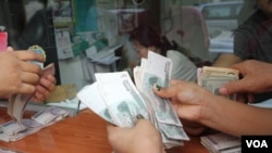 FILE: Cambodians count Cambodia's currency riels also the U.S's dollar at a local Money Exchange counter in Phnom Penh, Cambodia, April 07th, 2016. (Leng Len/VOA Khmer)
