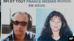 Pictures of French RFI journalists, Ghislaine Dupont, right, and Claude Verlon on a poster headed "RFI and all France Media World in Mourning" displayed in a window in Paris, Nov. 3, 2013. 