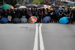 Protesters face off against riot police at the entrance to a village at Yuen Long district in Hong Kong, July 27, 2019. Protesters wearing black streamed through Yuen Long, even though police refused to grant permission for the march.