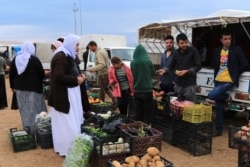 Displaced people from the Yazidi religious minority buy vegetables at the Sharya camp, in Duhok, Iraq, Oct. 29, 2019.