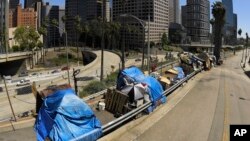FILE - This May 21, 2020, file photo shows a homeless encampment on Beaudry Avenue as traffic moves along Interstate 110 in downtown Los Angeles. Over three days and nights this week, census takers are going to shelters, soup kitchens, mobile food van sto