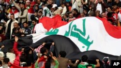 Para fans timnas sepak bola Irak meneriakan yel-yel sebelum pertandingan antara Irak dan Qatar pada ajang Piala Teluk Arab digelar di Stadion Internasional Basra di Basra, Irak, pada 16 Januari 2023. (Foto: AP/Nabil al-Jurani)