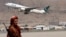 FILE - A Taliban fighter stands guard as a Pakistan International Airlines plane, the first commercial international flight to land after the Taliban retook power, takes off at the airport in Kabul on Sept. 13, 2021.