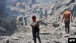 شماری از فلسطینی‌ها در کمپ مهاجرین الشاطی در میان خانه‌های ویرانه شده 