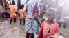 A child stands in floodwaters at a camp for people displaced by violence, Bentiu, South Sudan (G. Joselow/VOA).