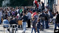 People wait outside a registration center for migrants and refugees in Berlin, Germany, Sept. 10, 2015 during visit of German Chancellor Angela Merkel at that center.