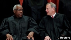 Hakim Mahkamah Agung AS Clarence Thomas (kiri) berbicara dengan hakim ketua John Roberts dalam sebuah kesempatan di gedung Mahkamah Agung di Washington, pada 30 November 2018. (Foto: Jim Young)