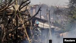 A firefighter extinguishes a blaze at the scene where a rocket launched from the Gaza Strip landed, causing fatalities, on a farm just over the Gaza border, in Moshav Ohad, southern Israel, May 18, 2021.