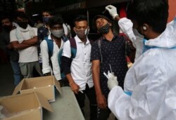 A health worker in protective suit collects nasal swab sample of a traveler to test for COVID-19 outside a train station in Bengaluru, India, June 16, 2021.