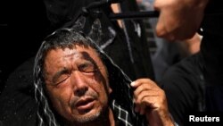 A Shiite Muslim man receives a spray of cold water to avoid heat during the Shiite Youm Ali procession in Karachi, Pakistan, June 27, 2016.
