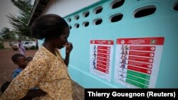 Seorang perempuan dan anak-anak melihat poster-poster pencegahan Ebola di sebuah sekolah Toulepleu di barat Pantai Gading, 4 November 2014. (Foto: Thierry Gouegnon/Reuters) 