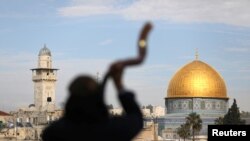 Seorang pria tampak dengan latar belakang Kubah Shakhrah (kanan), di kota tua Yerusalem di kompleks yang dikenal oleh umat Muslim sebagai tempat suci dan disebut "Temple Mount" oleh umat Yahudi.