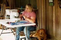 In this April 11, 2020, photo, Cathia Schmarje sews a face mask on the front porch of her home in Liberty County, Florida. She's sewn masks for her son and his employees, and she'll give some to townsfolk who need one. (AP photo)