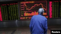 An investor watches an electronic board showing stock information on the first trading day after the week-long Lunar New Year holiday at a brokerage house in Beijing, China, Feb. 15, 2016. 