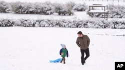 ທ້າວ ເຮັນ​ຣີ ມິ​ລ​ເລີ, ຊ້າຍ, ຍ່າງ​ຂຶ້ນ​ຄ້ອຍ​ທີ່​ເຕັມ​ໄປ​ດ້ວຍ​ຫິມ​ະ​ກັບ​ພໍ່​ຂອງ​ລາວ, ນະ​ຄອນ ແນ​ສວິ​ລ, ລັດ ເທັນ​ເນັ​ສ​ຊີ, 11 ມັງ​ກອນ 2025.