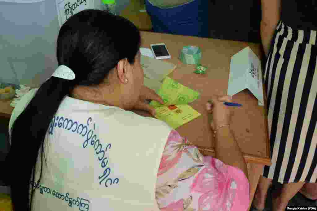 A worker at a polling station inspects a clean ballot, Yangon, Nov. 8, 2015.