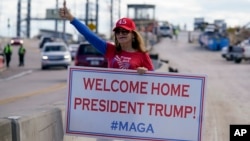 A supporter of President Donald Trump waits for the motorcade on the road to Mar-a-Lago, Trump's Palm Beach estate, on Wednesday, Jan. 20, 2021, in West Palm Beach, Fla. 