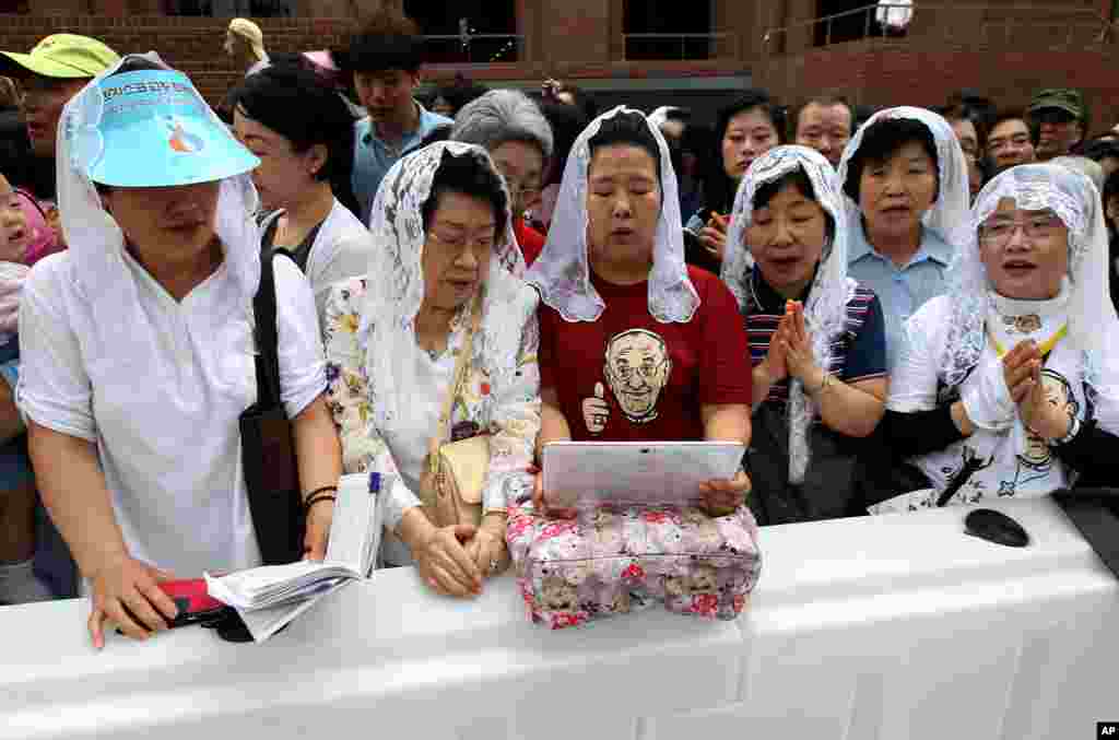 The faithful watch a laptop computer broadcasting a Mass of reconciliation outside Myeongdong Cathedral in Seoul, South Korea, Aug. 18, 2014.