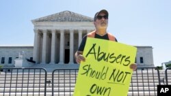 21일 미국 연방대법원 앞에서 패트릭 마호니 목사가 가정폭력 전력이 있는 사람에게 총기소지를 금지한 것은 정당하다는 푯말을 들고 서 있다. 