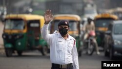 A traffic policeman wears a mask to protect himself from air pollution at a junction during restrictions on private vehicles based on registration plates, on a smoggy morning in New Delhi, India, November 4, 2019. 