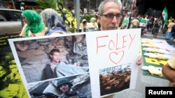 A man holds up a sign in memory of U.S. journalist James Foley during a protest against the Assad regime in Syria in Times Square in New York August 22, 2014. 
