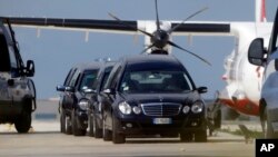 Mortuary vehicles wait outside a hangar where some of the bodies of Thursday's shipwreck are held, at the airport of Lampedusa, Italy, Oct. 4, 2013. 