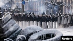 Polisi berjaga-jaga di tempat bentrokan dengan para demonstran anti-pemerintah di Kyiv (24/1).