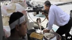 In this image made from video and accessed Saturday, Sept. 1, 2012, a Free Syrian Army fighter takes cover as another fighter fires at Syrian Army positions in Aleppo.
