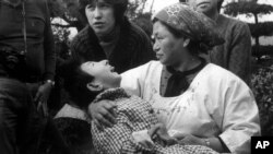 Seorang ibu memeluk korban "Penyakit Minamata" atau keracunan air raksa di Minamata, Jepang dalam arsip foto tahun 1973. Konvensi MInamata, perjanjian global untuk membatasi penambangan dan penggunaan merkuri mulai berlaku Rabu (16/8).