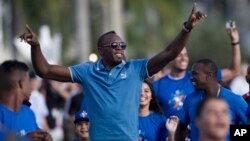 Pelari Jamaika dan juara olimpiade Usain Bolt saat berlari dengan atlet-atlet muda dalam sebuah kampanye mendorong olahraga di Rio de Janeiro, Brazil, Maret 2013. (AP/Felipe Dana)