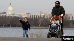 FILE - A man walks with his children during unseasonably warm weather in Washington, Feb. 22, 2017. 