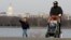 FILE - A man walks with his children during unseasonably warm weather in Washington, Feb. 22, 2017. 