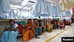 Para pekerja beristirahat pada jam makan siang di perusahaan tekstil di India. 