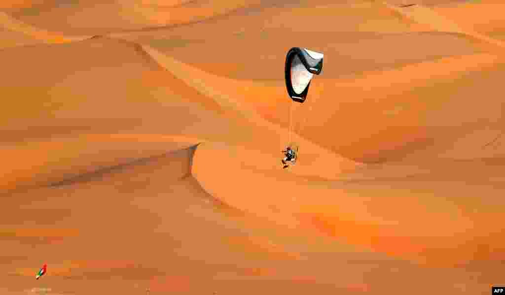 Seorang pria menerbangkan paramotor (parasut bermotor) di atas bukit pasir, di padang pasir Liwa sebelah barat Abu Dhabi, Uni Emirat Arab. 