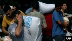 Palestinians collect bags of dried pulses from a UN-run aid supply center in Deir al-B, Gaza, on Oct. 28, 2023.