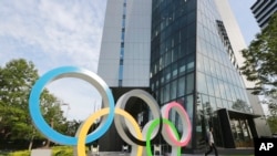 A man walks past the Olympic rings in Tokyo, Monday, June 7, 2021. (AP Photo/Koji Sasahara)