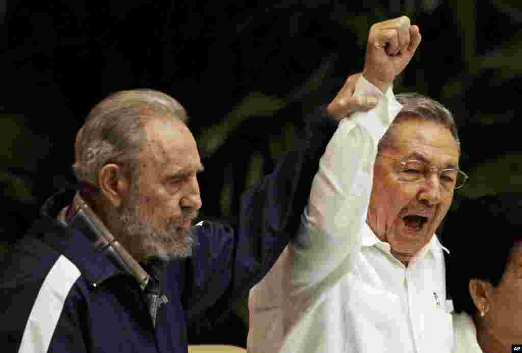 Fidel Castro mengangkat tangan adiknya, Presiden Kuba Raul Castro (tengah), saat mereka berdua menyanyikan lagu wajib sosialisme internasional dalam Kongres Partai Komunis ke-6 di Havana, 19 April 2011. (AP/Javier Galeano)