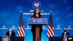 FILE - Vice President-elect Kamala Harris speaks during an introduction of President-elect Joe Biden's nominee for Secretary of Education, Miguel Cardona, seated left, at The Queen Theater in Wilmington, Del., Dec. 23, 2020. 