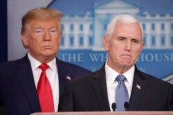 President Donald Trump, left, listens to Vice President Mike Pence, right, as he pauses while speaking to members of the media to address the nation about the coronavirus threat.