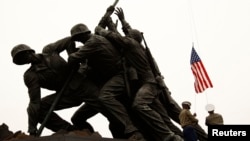 U.S. flags are briefly raised, saluted, then lowered by U.S. Marines during a ceremony honoring members of the military at the Iwo Jima Memorial (also called the U.S. Marine Corps War Memorial) in Arlington, Virginia, March 5, 2012. 