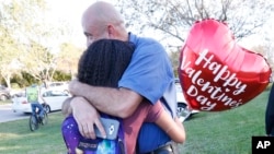 Family members embrace following a shooting at Marjory Stoneman Douglas High School, Feb. 14, 2018, in Parkland, Fla.