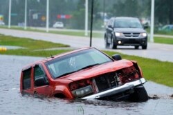 Sebuah kendaraan terlihat setengah tenggelam di parit, di sebelah jalan bebas hambatan di Bay Sain Louis, Mississippi yang terancam banjir di hantaman badai Ida, Minggu, 29 Agustus 2021. (Foto AP / Steve Helber)