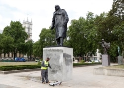 A council employee cleans graffiti from the statue of Winston Churchill at Parliament Square