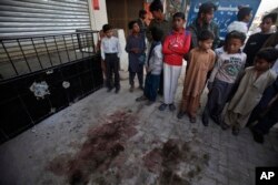 FILE - Youngsters gather at spot where Nasiruddin Haqqani, a senior leader of the feared militant Haqqani network, was assassinated at an Afghan bakery in the Bhara Kahu area on the outskirts of Islamabad, Pakistan, Nov. 11, 2013.