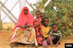 A woman sits with children near a water tower in Kenya’s Dadaab refugee camp on Sept. 19, 2016. (J. Craig/VOA)