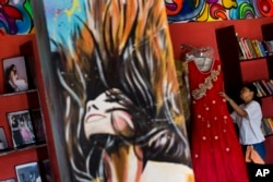 FILE - Acid attack survivor Rupa, 22, arranges some of her creations displayed at "Sheroes Hangout" café, managed by five acid attack survivors in Agra, India, Nov. 25, 2014.