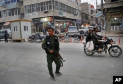 FILE - A member of the Kurdish internal security forces patrols a commercial street in Manbij, north Syria, March 28, 2018. Manbij, a mixed Arab and Kurdish town of nearly 400,000, was liberated from Islamic State militants in 2016 by the YPG fighters with backing from U.S-led coalition airstrikes.