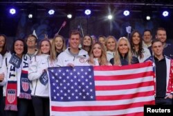 FILE - Olympians hold a flag at an event in Times Square to celebrate 100 days from the start of the Pyeongchang 2018 Olympic Games in South Korea, in New York, Nov. 1, 2017.